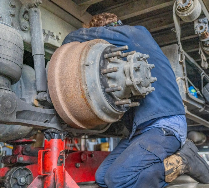Truck mechanic repairing brake drum and hub assembly on heavy-duty semi truck